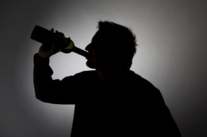 Man drinking from a wine bottle, silhouette